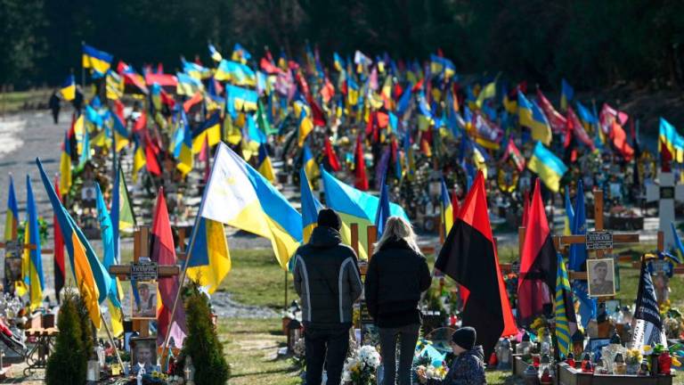 Visitors stand at a grave at Lychakiv military cemetery in Lviv, western Ukrainian on March 18, 2023, amid the Russian invasion of Ukraine/AFPPix