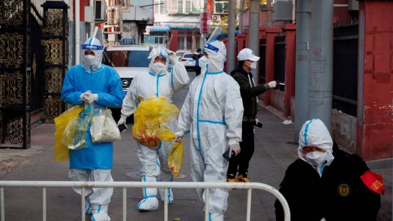 Epidemic prevention workers in protective suits walk in a locked-down residential compound as outbreaks of the coronavirus disease (Covid-19) continue in Beijing, November 23, 2022. - REUTERSPIX