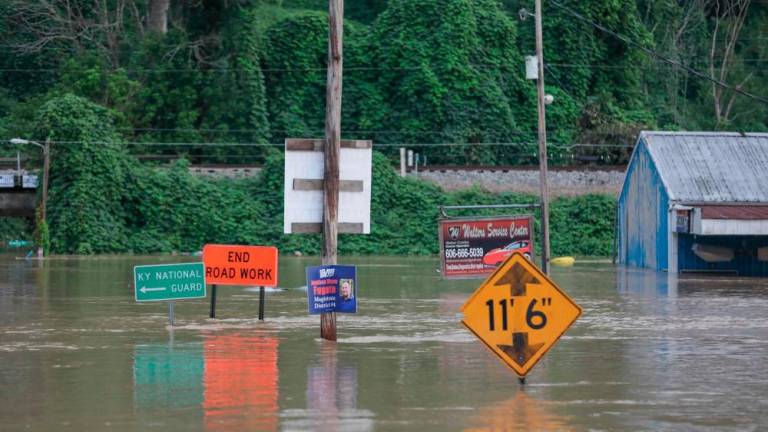 Road signs are barely visible on a road covered by floodwaters from the North Fork of the Kentucky River in Jackson, Kentucky on July 28, 2022. AFPPIX