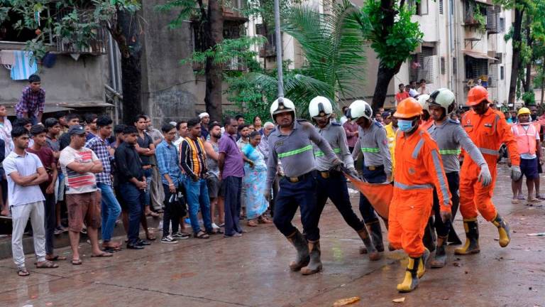 Rescue workers carry a dead body of a victim from the debris of a collapsed building in Mumbai on June 28, 2022. AFFPIX