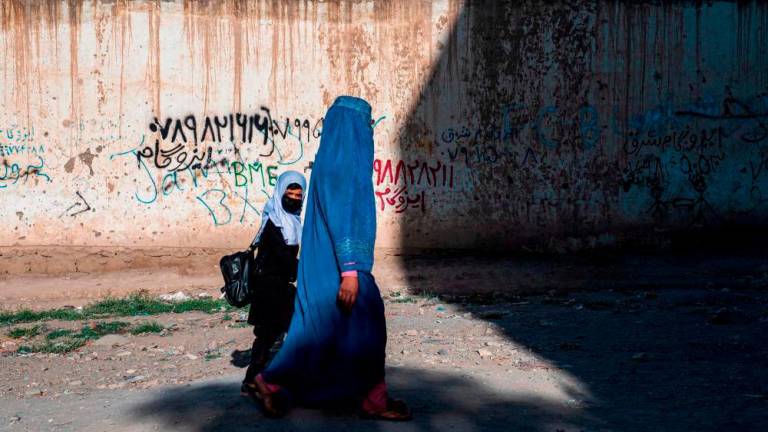 In this picture taken on August 9, 2022, an Afghan woman and a girl walk to a primary school in Kabul. - AFPPIX