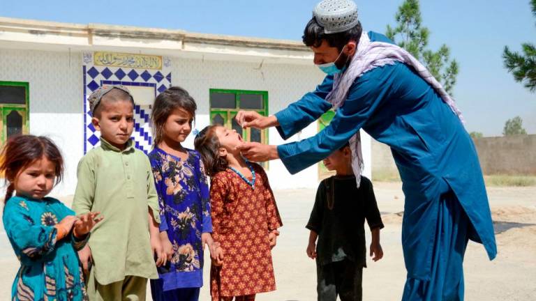 A health worker administers polio vaccine drops to a child during a polio vaccination campaign in Kandahar on May 23, 2022. AFPPIX