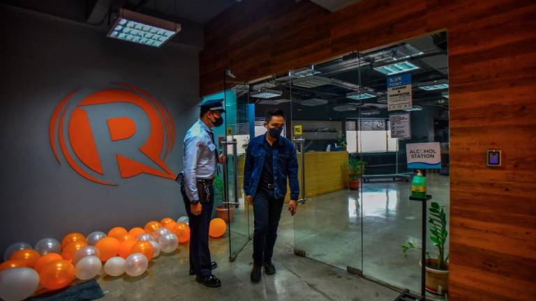 An employee of news online portal Rappler walks past the company logo at their office in Pasig City, suburban Manila. – AFPPIX