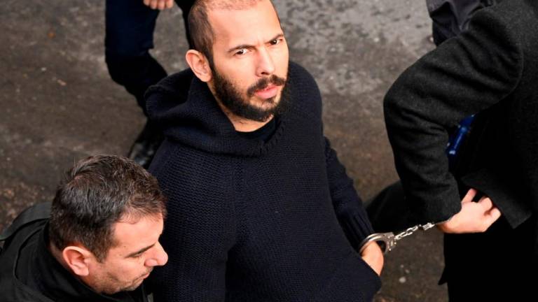In this file photo taken on February 01, 2023 British-US influencer Andrew Tate arrives handcuffed and escorted by police at a courthouse in Bucharest on February 1, 2023 to hear the court decision on his appeal against pre-trial detention for alleged human trafficking, rape and forming a criminal group. AFPPIX
