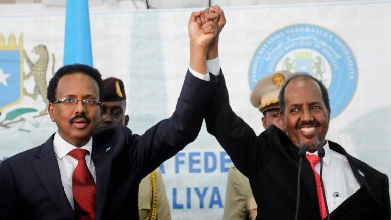 Somalia's newly elected president Hassan Sheikh Mohamud holds hands with incumbent president Mohamed Abdullahi Mohamed after winning the elections in Mogadishu, Somalia May 16, 2022. REUTERSPIX