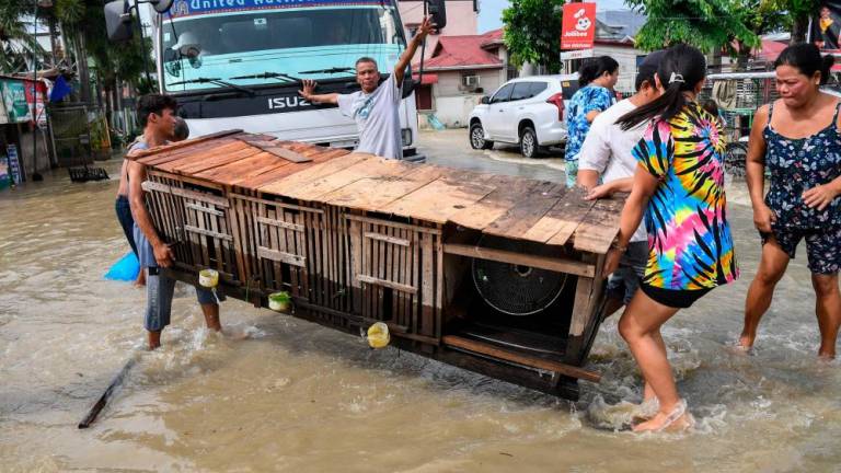 Residents carry an animal cage while evacuating from their submerged homes in the aftermath of Super Typhoon Noru in San Ildefonso, Bulacan province on September 26, 2022. AFPPIX