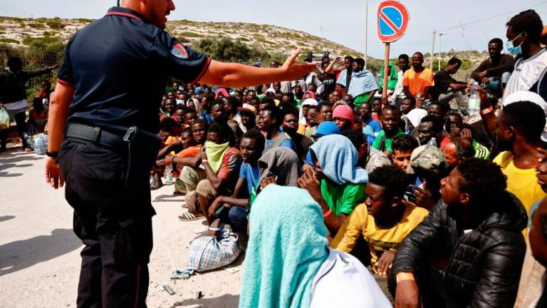 A member of the Carabinieri gestures towards migrants outside the hotspot, on the Sicilian island of Lampedusa, Italy, September 16, 2023. REUTERSPIX