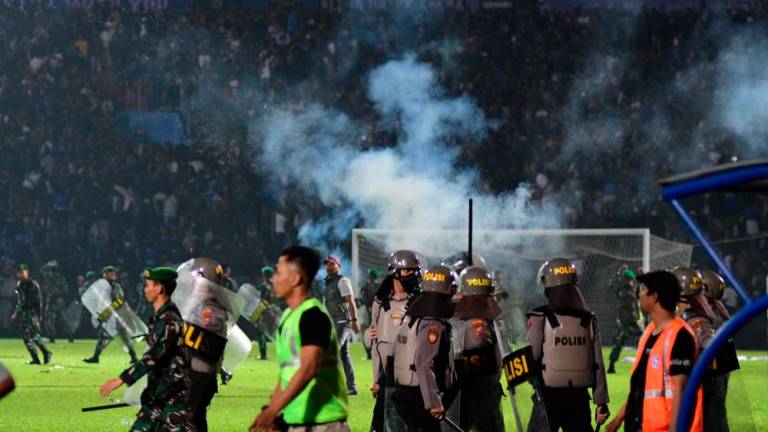 This picture taken on October 1, 2022 shows tear gas let off by police amongst people crowded in the stands after a football match between Arema FC and Persebaya at the Kanjuruhan stadium in Malang, East Java. AFPPIX