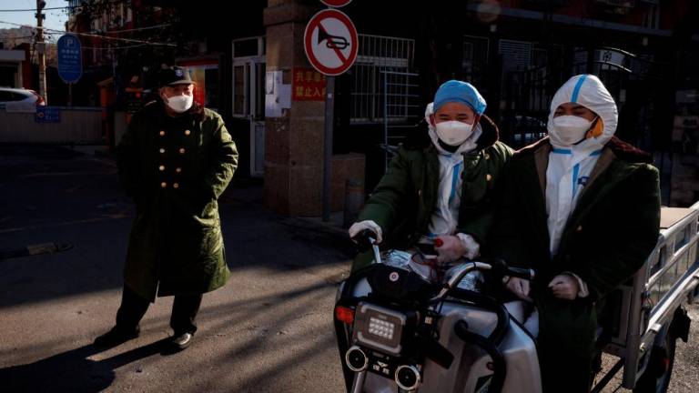 Pandemic prevention workers in protective suits ride an electric vehicle as coronavirus disease (Covid-19) outbreaks continue in Beijing, December 4, 2022. - REUTERSPIX