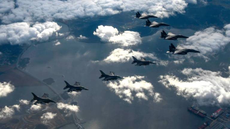 This handout photo taken on October 4, 2022 and provided by the South Korean Defence Ministry in Seoul shows four South Korean Air Force F-15Ks and four US Air Force F-16 fighters flying over South Korea, during a precision bombing drill in response to North Korea firing an Intermediate Range Ballistic Missile over Japan. - AFPPIX