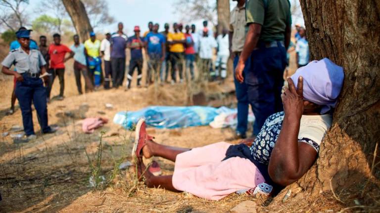 A distraught woman collapses after identifying the body of a miner strapped on a stretcher after a gold mine shaft collapsed at the Bay Horse mine in Chegutu, Zimbabwe on September 30, 2023. - AFPPIX
