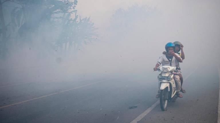 Residents brace as they travel through smog due to wildfires in North Indralaya, South Sumatra. Transboundary haze may affect Malaysia depending on wind conditions.. - REUTERSPIX