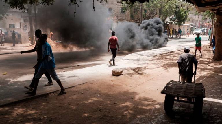 People walk through a busy neighbourhood as fires are lit in Dakar on June 1, 2023, during unrest following the sentence of opponent Ousmane Sonko. AFPPIX