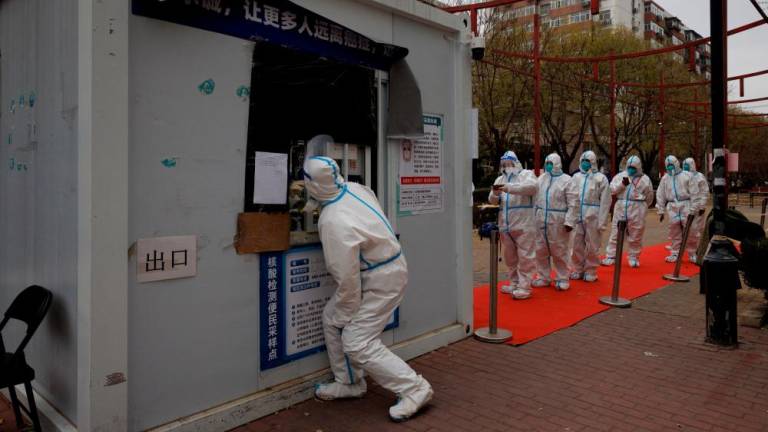 Epidemic-prevention workers line up to get swab tested on Monday. Chinese health officials say the country plans to speed up Covid-19 vaccinations for elderly people. – Reuterspic