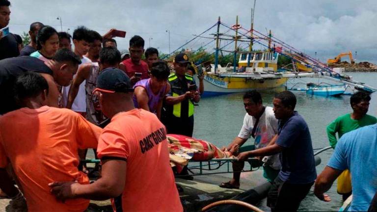 This handout photo taken on October 3, 2023 and released by the Philippine Coast Guard on October 4, 2023 shows personnel retrieving the body of a crew member of a Filipino fishing boat in Infanta, after their boat was rammed by a foreign commercial vessel on October 2 about 160 kilometres northwest of Scarborough Shoal, off the Philippines' main island of Luzon. AFPPIX