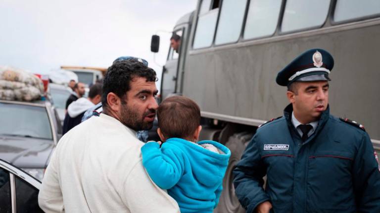 A refugee carrying a child speaks with a policeman upon his arrival with his family and after crossing the border at a registration centre of the Armenian foreign affairs ministry, near the border town of Kornidzor, on September 25, 2023. AFPPIX
