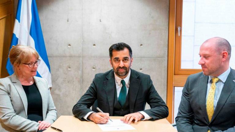 Newly elected leader of the Scottish National Party (SNP), Humza Yousaf (C), signs the nomination form to become First Minister for Scotland, flanked by his proposer Shona Robison (L) and seconder Neil Gray (R), at the Scottish Parliament in Edinburgh, ahead of the MP’s vote concerning his nomination to be Scotland’s sixth First Minister. AFPPIX