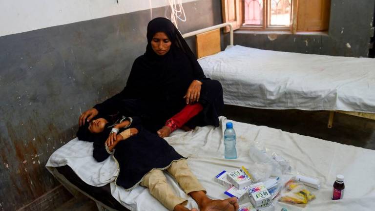In this picture taken on September 27, 2022, an internally displaced flood-affected woman takes care of her daughter being treated at a hospital in Johi, Dadu district of Sindh province. AFPPIX