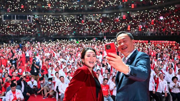 Pheu Thai Party’s prime ministerial candidates Paetongtarn Shinawatra (L) and Srettha Thavisin (R) take a selfie photo on stage at the party’s final campaign event in Bangkok on May 12, 2023, ahead of Thailand’s May 14 general election. AFPPIX