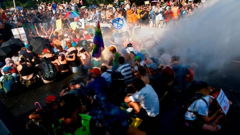 People sit next to a water cannon, as climate activists block the A12 highway in The Hague, Netherlands, September 9, 2023. REUTERSPIX