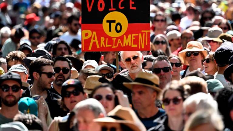 Crowds hold up a placard of the Australian Aboriginal Flag during a Walk for Yes rally for the upcoming Voice referendum in Melbourne on September 17, 2023. AFPPIX