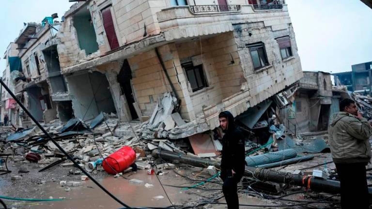 Penduduk berdiri di hadapan bangunan runtuh berikutan gempa bumi di bandar Jandaris, di kawasan luar bandar Afrin di barat laut Syria di bahagian wilayah Aleppo yang dikuasai pemberontak, pada 6 Februari 2023. fotoAFP