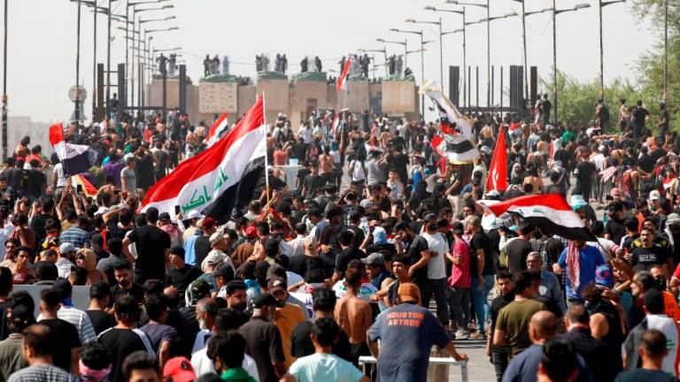 Iraqi anti-government demonstrators wave the national flag as they attend a protest in Tahrir Square in the centre of Iraq’s capital Baghdad on October 1, 2022. AFPPIX