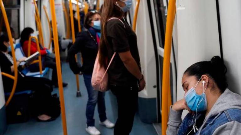 FILE PHOTO: A commuter wearing a protective mask sleeps inside a metro coach, on the first day mask usage is mandatory in public transport, amid the coronavirus disease (Covid-19) outbreak in Madrid, Spain, May 4, 2020. REUTERSPIX