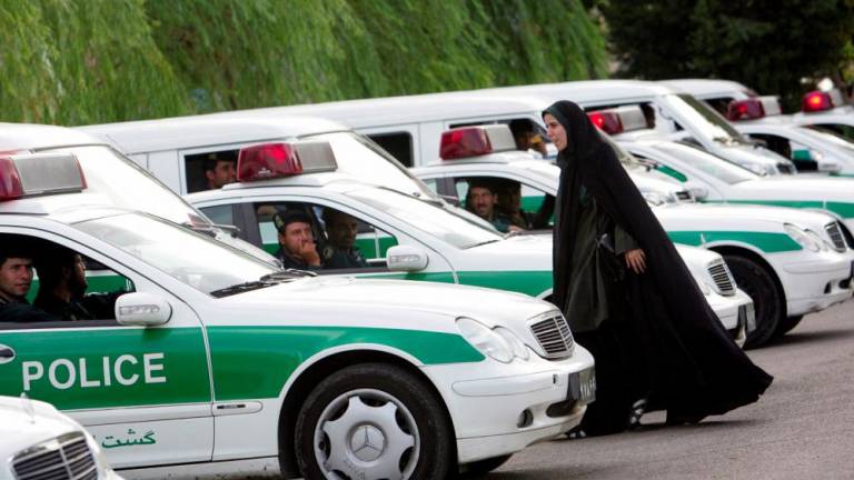 (FILES) In this file photo taken on July 23, 2007, An Iranian policewoman (R) walks between police vehicles, preparing to start a crackdown to enforce Islamic dress code in the capital Tehran. - AFPPIX