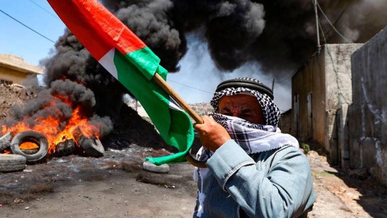 An elderly Palestinian man holds a national flag during clashes with Israeli forces following a demonstration against the expropriation of Palestinian land by Israel, in the village of Kfar Qaddum near the Jewish settlement of Kedumim in the occupied West Bank, on July 1, 2022. AFPPIX