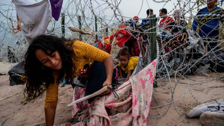 Migrants from Venezuela crawl through a hole in the razor wire to cross into Eagle Pass, Texas on September 25, 2023. AFPPIX