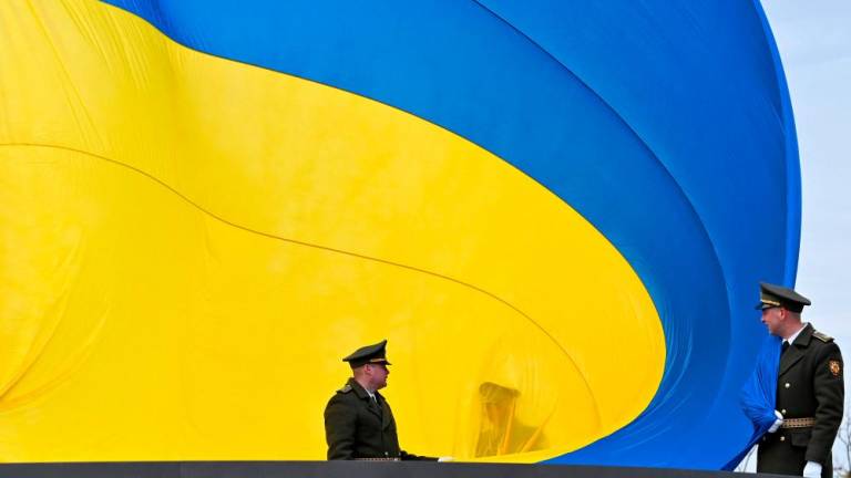 Ukrainian servicemen hold the huge national flag before it raises to the flagpole during a ceremony marking the first anniversary of the retreat of Russian troops from the Ukrainian town of Bucha, in Bucha, near Kyiv, on March 31, 2023. AFPPIX