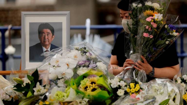 FILE PHOTO: A mourner offers flowers next to a picture of late former Japanese Prime Minister Shinzo Abe, who was shot while campaigning for a parliamentary election, on the day to mark a week after his assassination at the Liberal Democratic Party headquarters, in Tokyo, Japan July 15, 2022. REUTERSPIX