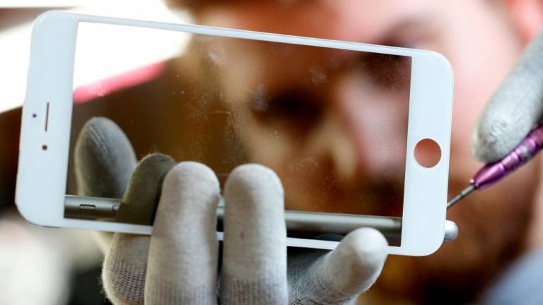 FILE PHOTO: A worker refurbishes an Apple Iphone cell phone at a workshop of the Oxflo company, specialised in refurbishment of broken European smartphones which will be resold and provided with a warranty as part of an eco-responsible approach, in Lusignac, France, June 20, 2019. - REUTERSPIX