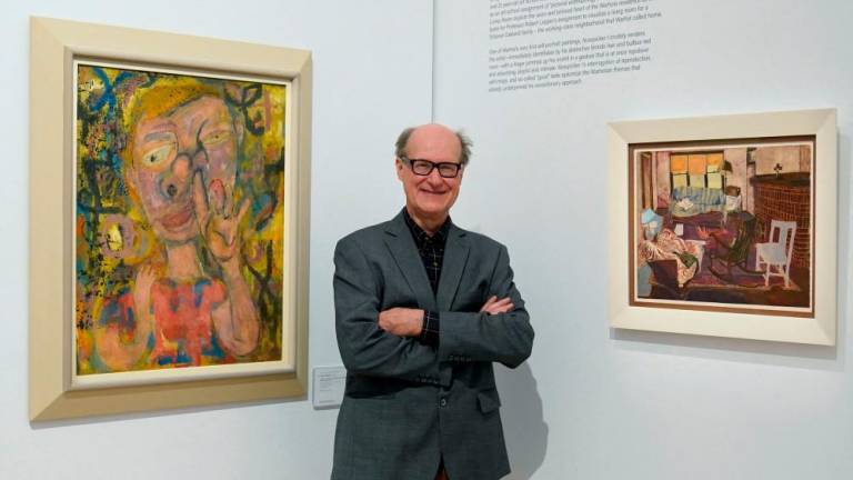 James Warhola, US artist and illustrator, stands next to his uncle Andy Warhol’s “Nosepicker 1: Why Pick on Me” and “Living Room” on display November 10, 2022 at Phillips Auction House in New York. AFPPIX