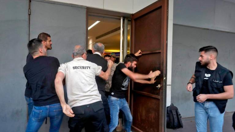 A policeman is stopped by security guards from entering a branch of BLOM Bank in the Lebanese port city of Saida (Sidon) on September 26, 2022 as banks reopened to depositors with scheduled appointments only, following a week of closure due to security concerns. AFPPIX