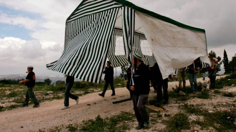 Israeli activists carry a tent in the abandoned Jewish settlement of Homesh, in the northern West Bank, March 27, 2007. REUTERSPIX