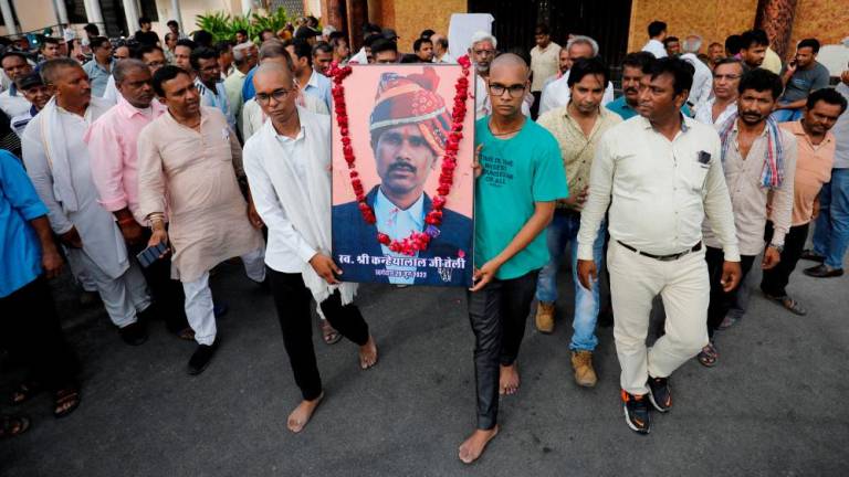 FILE PHOTO: Two sons of Kanhaiyalal Teli, a Hindu tailor, who was killed by two suspected Muslims after they videoed themselves slaying him, carry a portrait of their father after a prayer meeting in Udaipur in the northwestern state of Rajasthan, India, June 30, 2022. REUTERSpix