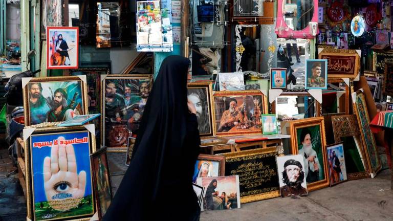 A woman walks past near pictures for sale in Baghdad, Iraq, February 3, 2023. REUTERSPIX
