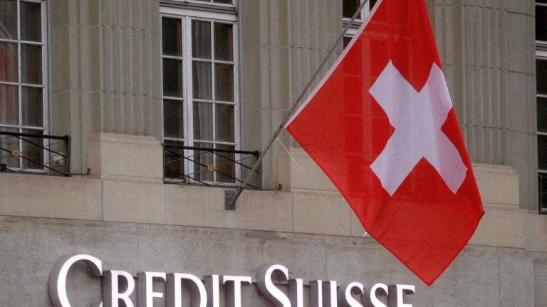 Switzerland’s national flag flies above a logo of Credit Suisse in front of a branch office in Bern, Switzerland. – Reuterspic
