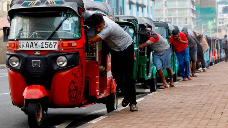 Drivers push auto rickshaws in a line to buy petrol from a fuel station amid Sri Lanka’s economic crisis, in Colombo, Sri Lanka, July 29, 2022. REUTERSpix