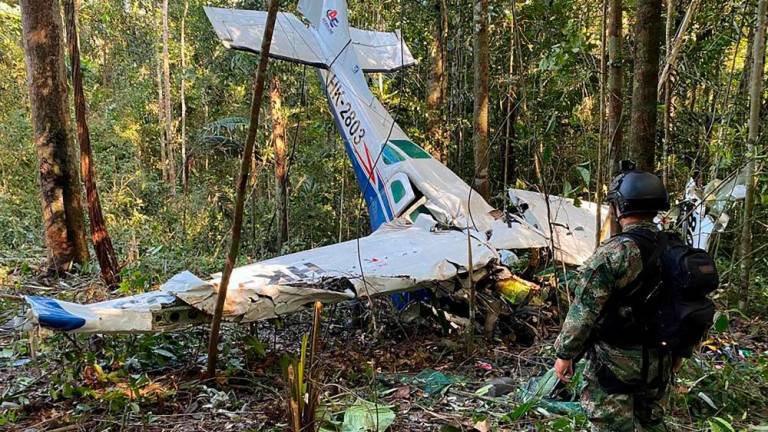Handout picture released by the Colombian Army showing a soldier standing next to the wreckage of an aircraft that crashed in the Colombian Amazon forest in the municipality of Solano, department of Caqueta, on May 19, 2023. AFPPIX