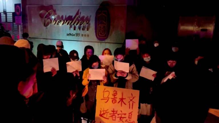 People hold signs during a candlelight vigil held for the victims of the Urumqi fire, in Shanghai, China November 26, 2022 in this picture obtained from a social media video. - REUTERSPIX