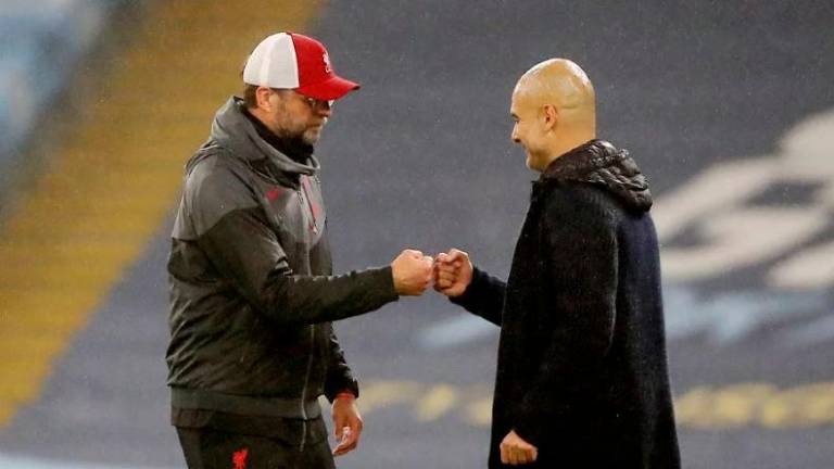 FILE PHOTO: Manchester City manager Pep Guardiola (right) and Liverpool manager Jurgen Klopp (left) bump fists after the match at the Etihad Stadium in Manchester on November 8, 2020. REUTERSPIX