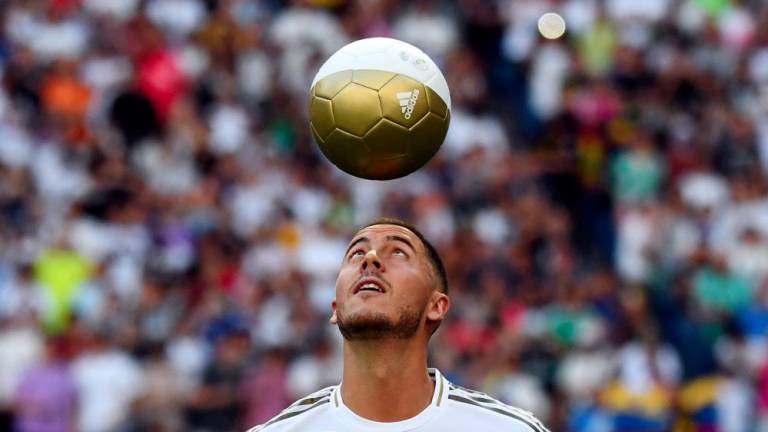 (FILES) In this file photo taken on June 13, 2019 Belgian footballer Eden Hazard plays with a ball during his official presentation as new player of the Real Madrid CF at the Santiago Bernabeu stadium in Madrid. - AFPPIX