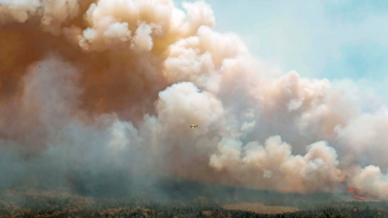 An aircraft from New Brunswick drops a mix of water and fire retardant over the fire near Barrington Lake, Shelburne County, Canada. AFPPIX
