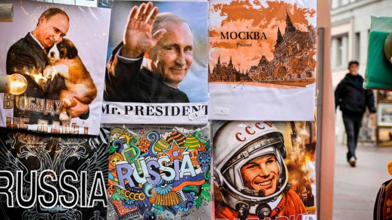 A man walks past t-shirts bearing images of Russian President Vladimir Putin and Yury Gagain, the first man in space, at a gift shop in downtown Moscow on October 6, 2022, on the eve of Vladimir Putin’s 70th birthday. AFPPIX