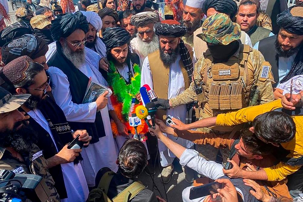 One of the last Afghan detainees held inside the Guantanamo Bay US detention centre in Cuba Asadullah Haroon (C, green garland) is surrounded by members of the media upon his arrival in Kabul/AFPPix