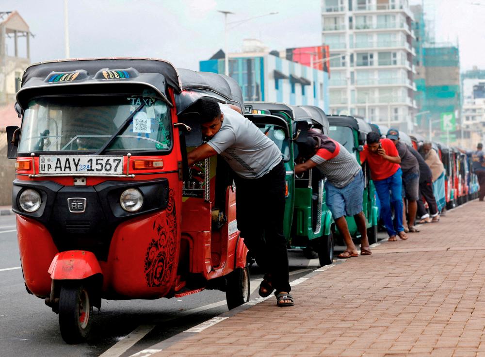Drivers pushing auto rickshaws in a line to buy petrol from a fuel station in Colombo, Sri Lanka, on July 29, 2022. According to a UN report, in 2022, debt servicing accounted for nearly 80% of Sri Lanka’s government revenue. – Reuterspic