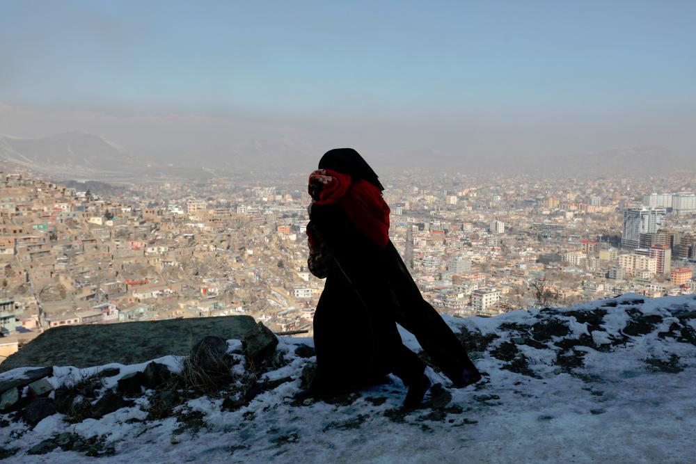 An Afghan woman holds her child as she walks on a snow-covered street on the TV mountain in Kabul, Afghanistan/ REUTERSPIC